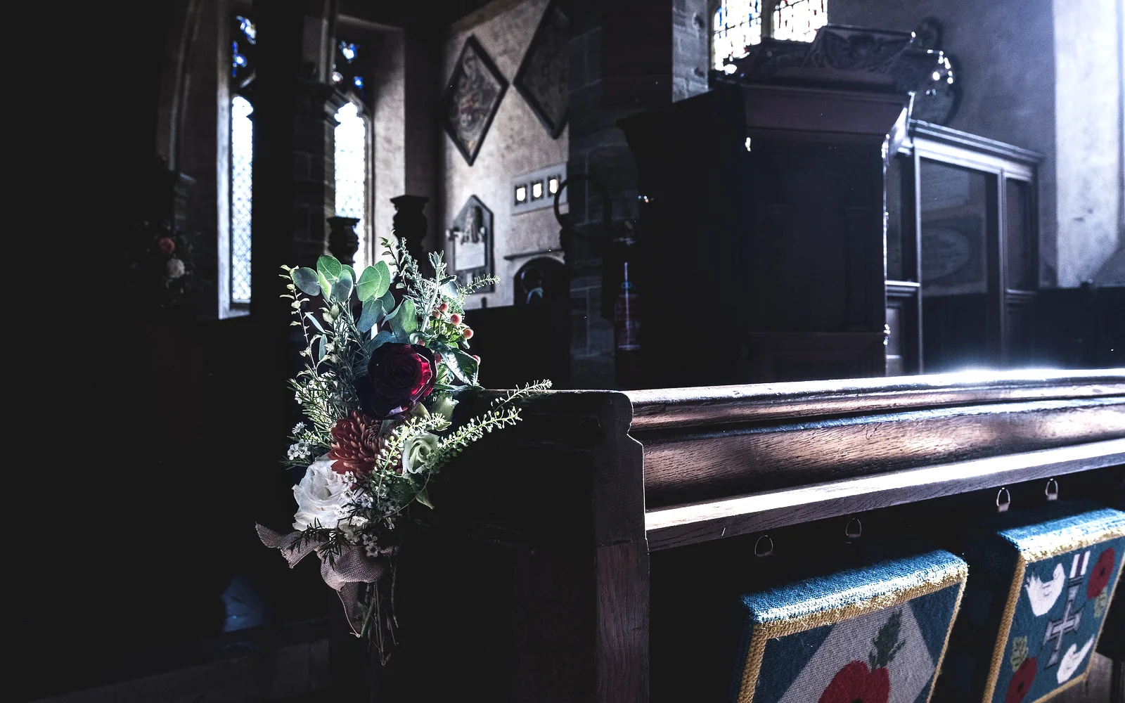 Church pew decorated with a bouquet of roses and greenery on a wedding morning