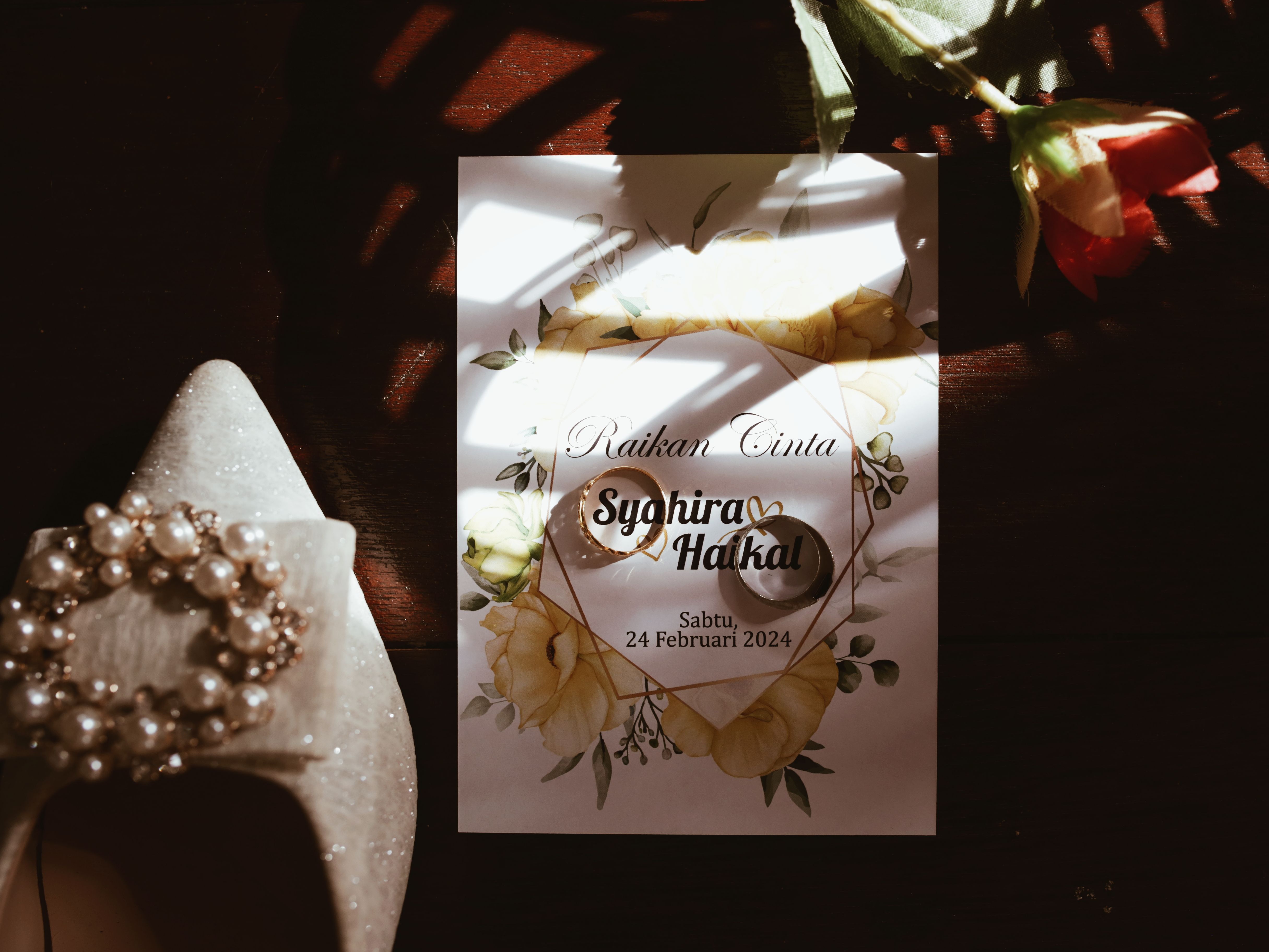 A grandmother and a young woman looking together at a wedding invitation on a smartphone screen at a kitchen table.