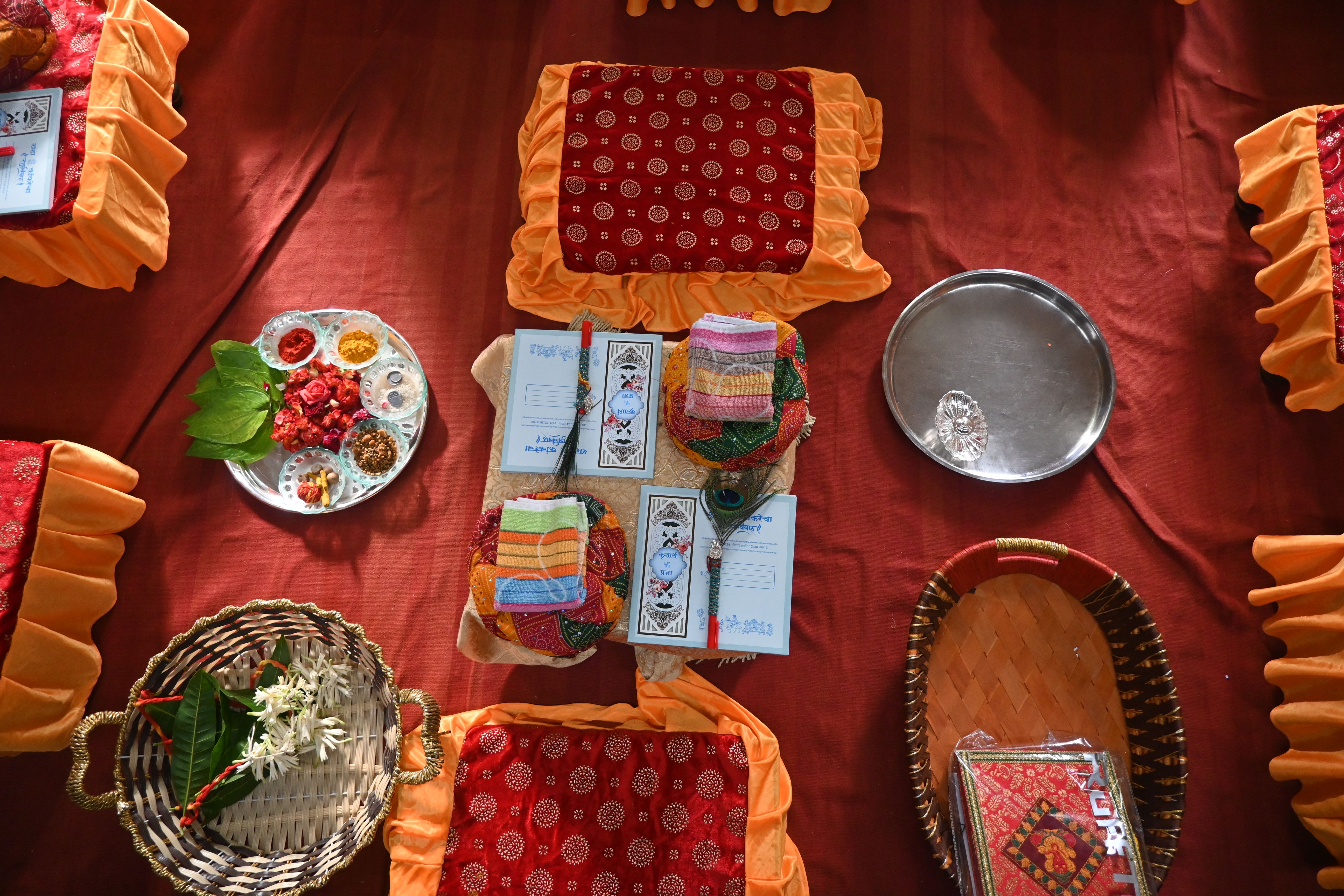 A traditional Hindu wedding invitation card in red and gold with an Om Ganesha motif at the top.