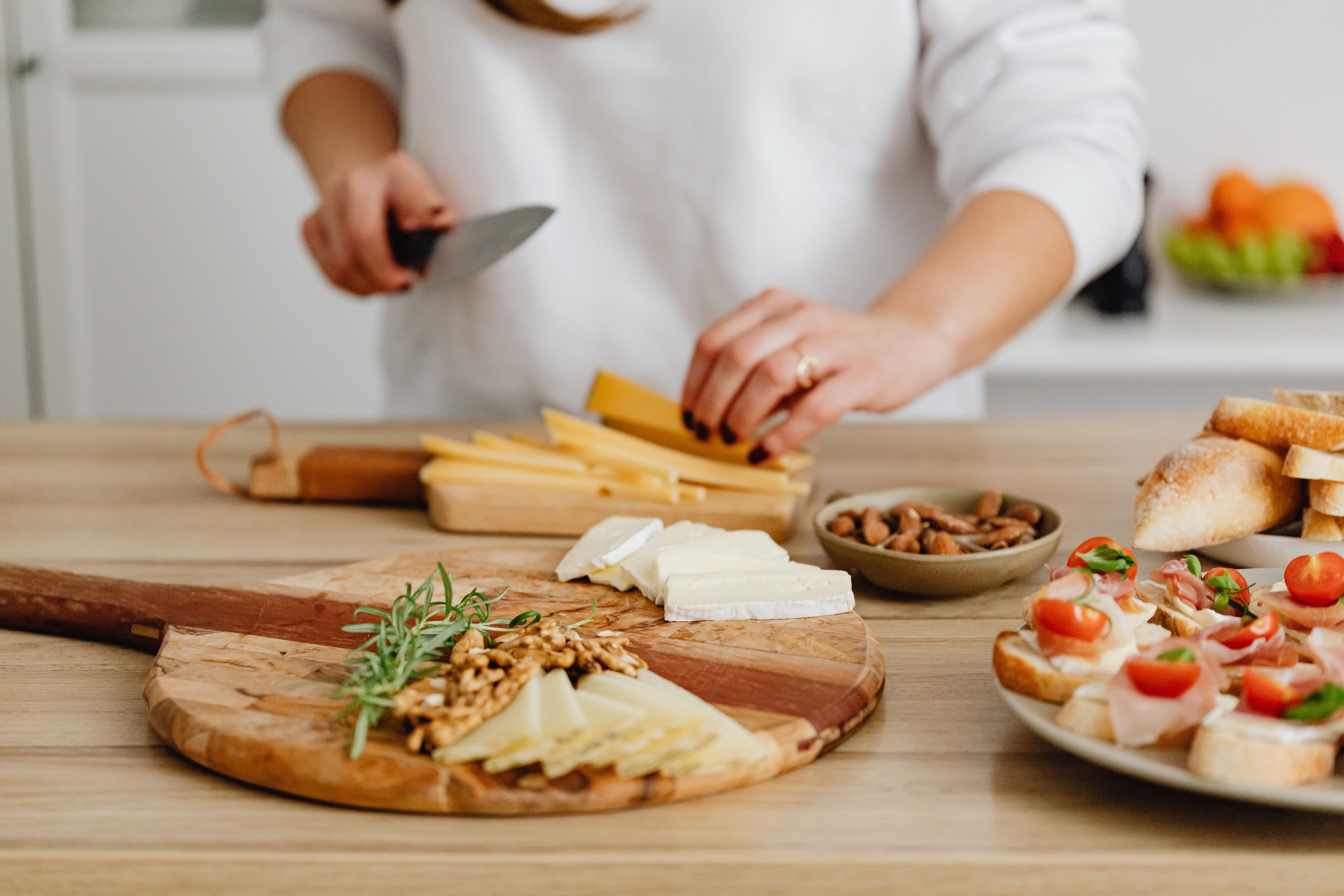 A party table set with trays of skewers, sliders, and a cheese board surrounded by small plates.