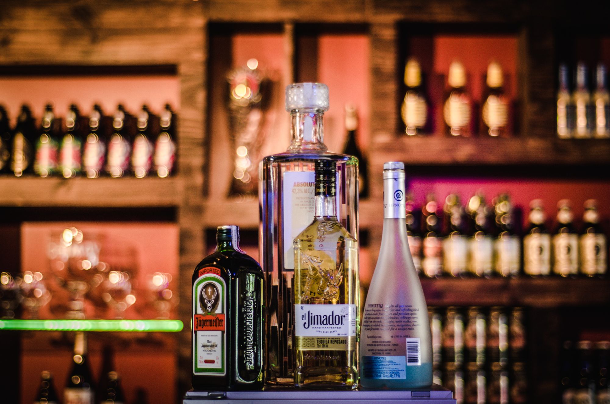 A home bar set up with bottles of spirits, wine, an ice bucket, and rows of glasses ready for guests.