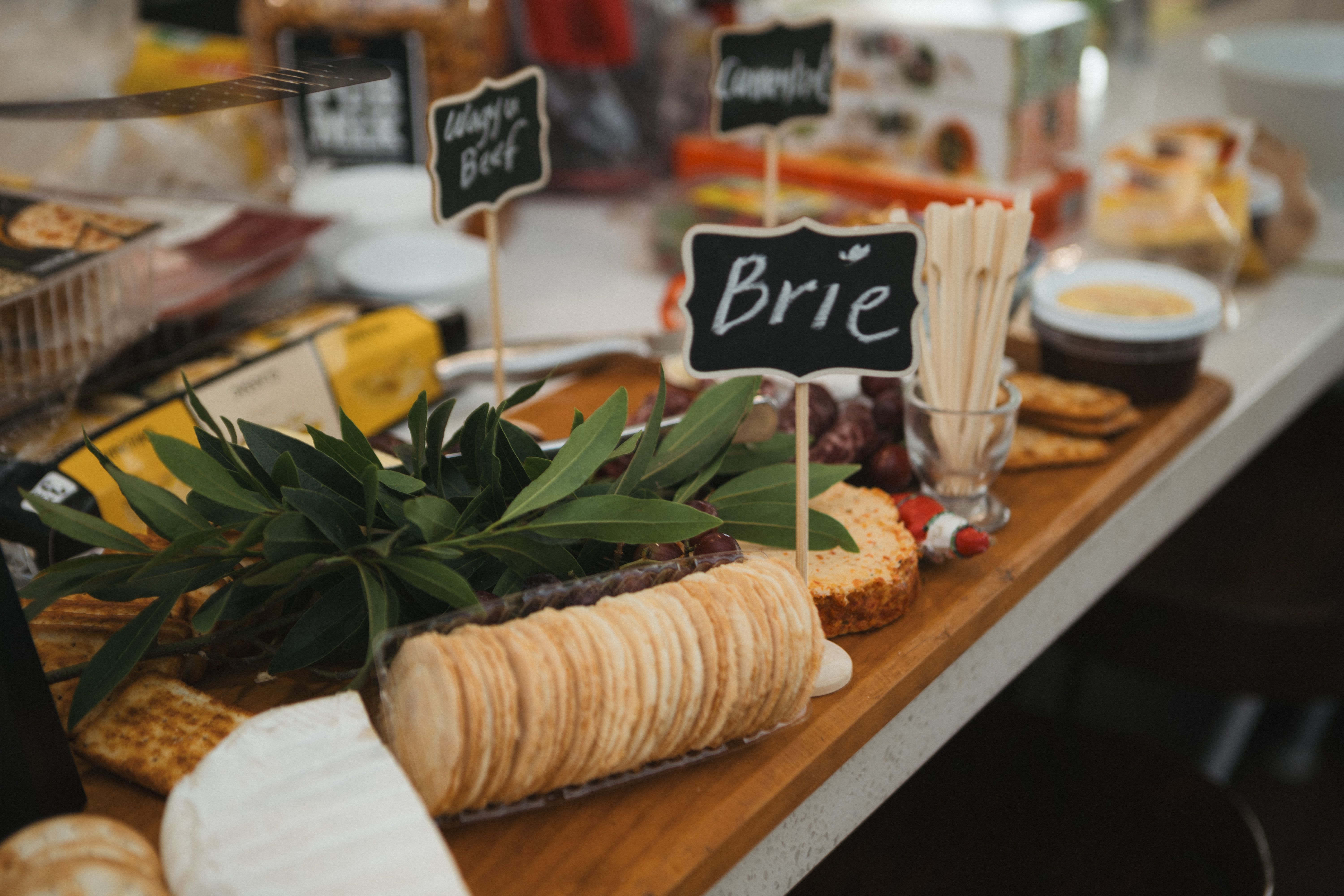 A backyard buffet table laid out with trays of grilled meat, salads, and rolls for a large group.