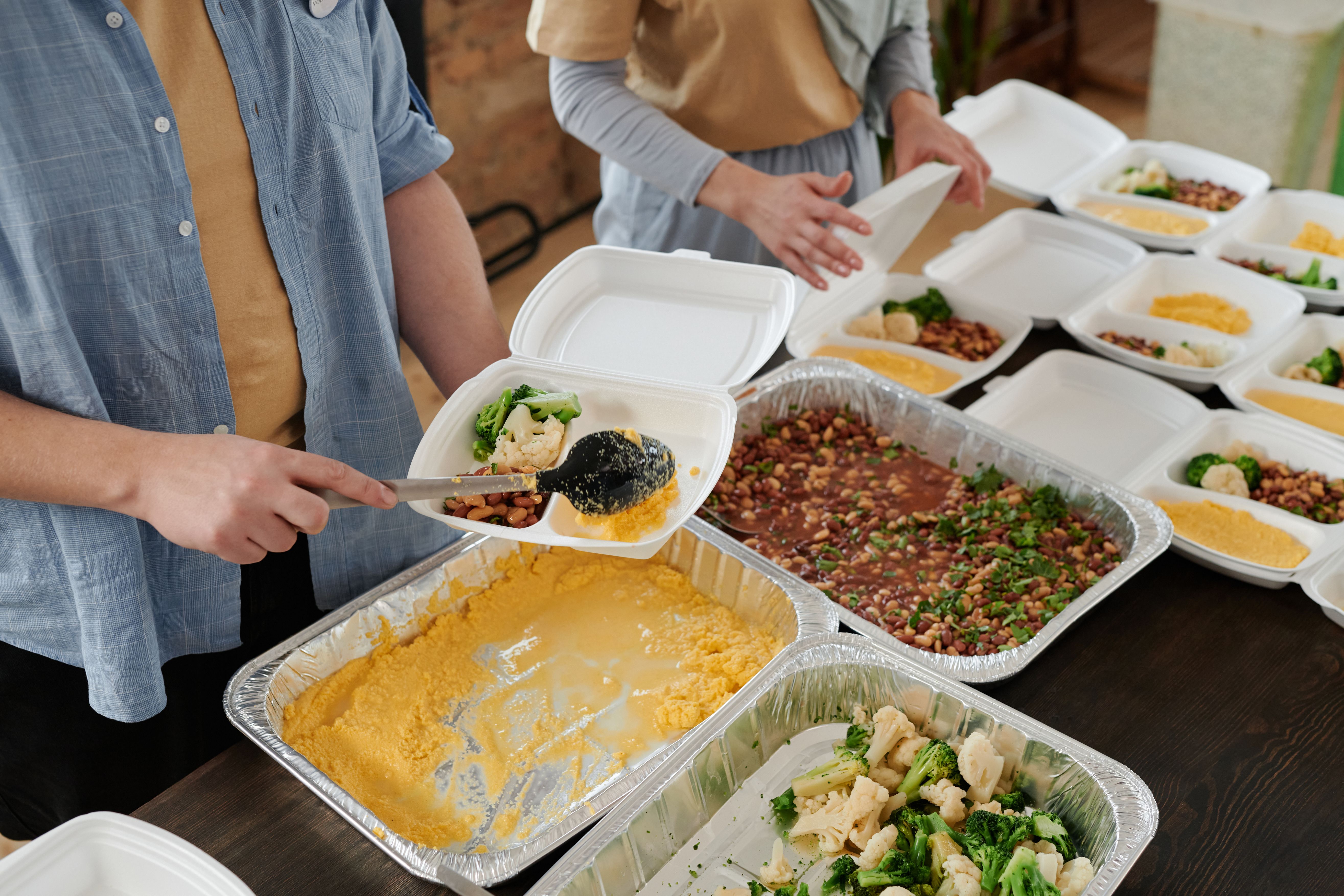 A long buffet table with trays of meat, vegetables, rice, and salad set out for a large gathering.