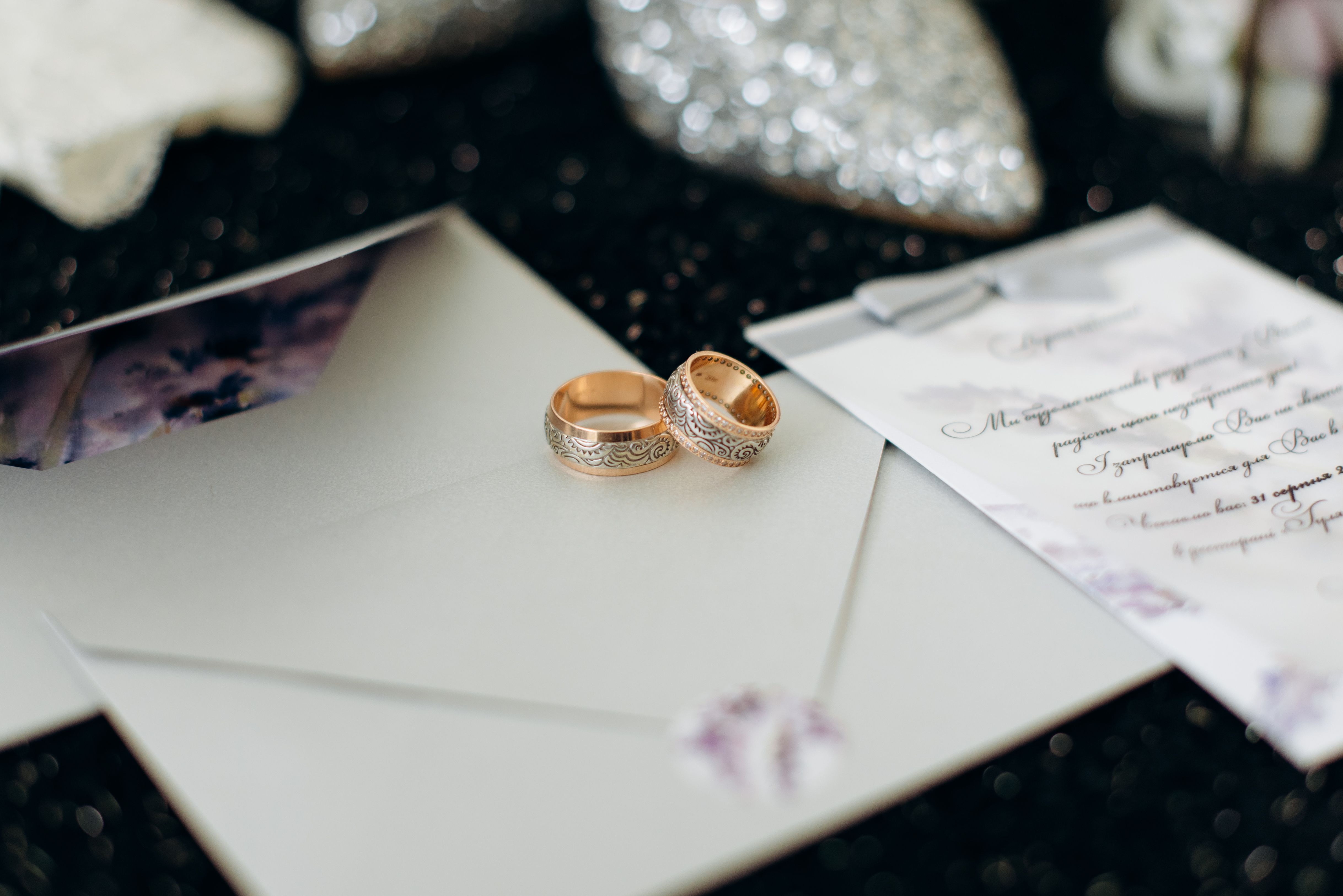 A small, elegantly designed Indian wedding invitation card resting beside fresh marigold flowers on a wooden table.
